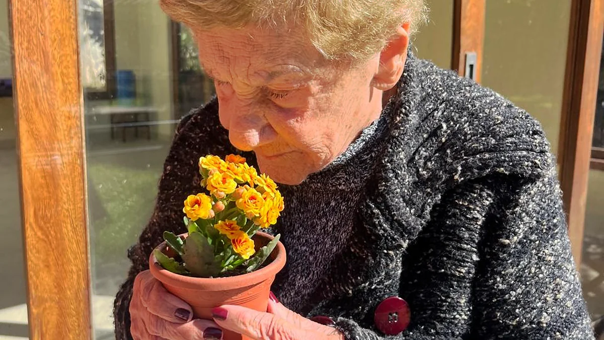 Hóspede cheirando um vaso de flores na Rede Vitória Spa
